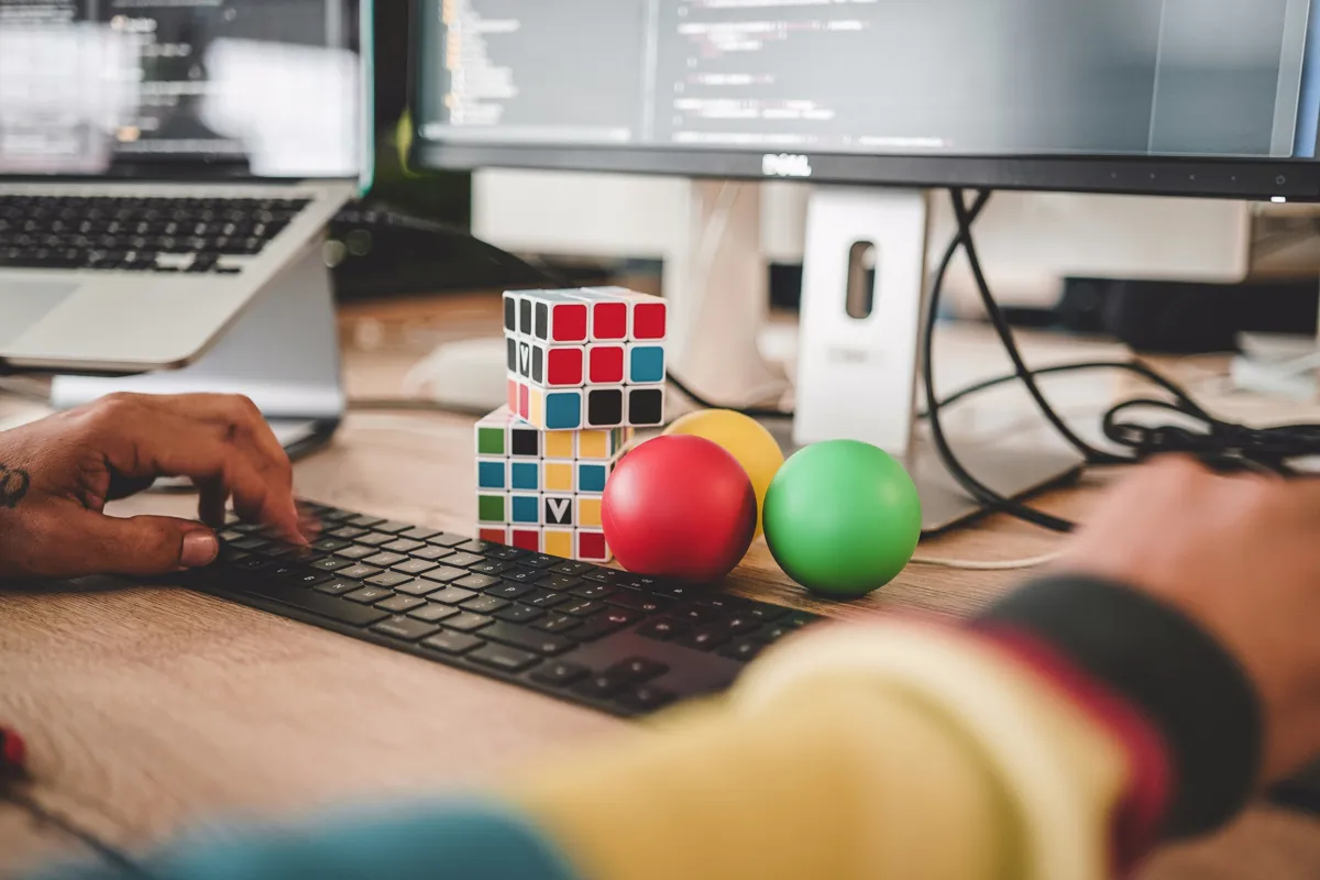 Miembro del equipo programando en su escritorio, con dos cubos de Rubik junto al monitor